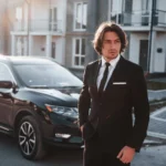 portrait-handsome-young-businessman-black-suit-tie-outdoors-near-modern-car-city